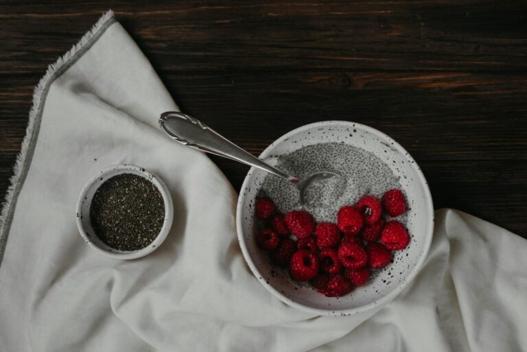 Delicious chia pudding topped with fresh raspberries and served with chia seeds on a rustic table setting.